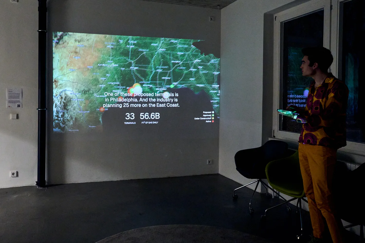 Wide shot of Lachlan in front of projection of map of U.S. L.N.G. terminals